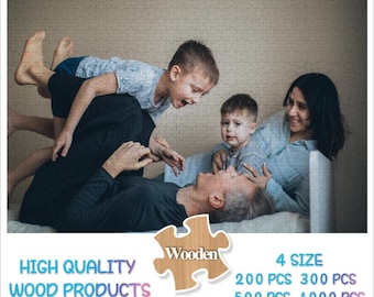 May include: A family of four is playing together. The father is lying on the floor, while the mother is sitting on the bed with their two children. The children are smiling and laughing. The image is a photo puzzle with the text "Wooden" and "High Quality Wood Products" on the bottom. The puzzle is available in four sizes: 200 pieces, 300 pieces, 500 pieces, and 1000 pieces.