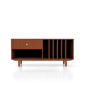 May include: A mid-century style wooden media console with a drawer, open shelf, and vertical dividers. The console is made of brown wood, has a gold-coloured knob, and sits on four tapered legs. The design is ideal for storing media and records.