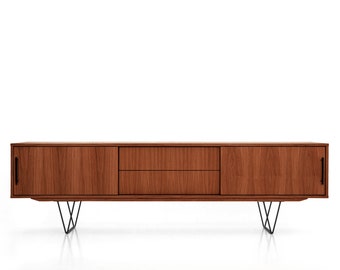 May include: A mid-century modern style wooden media console with two doors, two drawers, and black hairpin legs. The console is a warm brown color and has black handles.