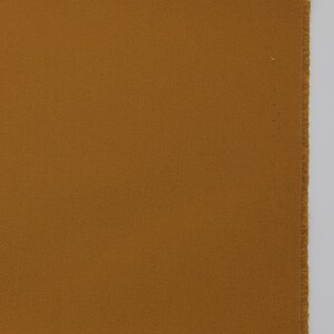 May include: A close-up of a piece of brown fabric with a subtle diagonal weave pattern.