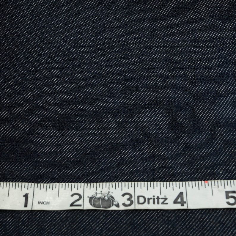 May include: Close-up of dark blue denim fabric with a white measuring tape that reads "1 inch 2 3 Dritz 4 5".