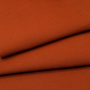 May include: Close-up of a rust-colored fabric with a subtle twill weave. The fabric is folded in thirds, showing the texture and color.