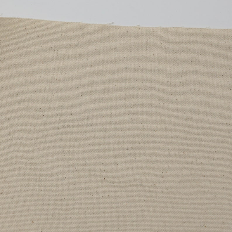 May include: A close-up of a plain, off-white canvas fabric with a subtle texture. The fabric has a slightly rough, natural feel.