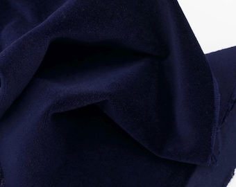 May include: Close-up of a dark blue velvet fabric. The fabric is soft and plush, with a subtle sheen.