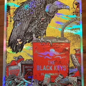 Puede incluir: Un póster de estilo vintage con un buitre negro posado sobre un bidón de gasolina rojo con el texto "The Black Keys" y "Flammable". El póster tiene un fondo amarillo con un estilo grunge desgastado e incluye varios otros objetos como una llave inglesa, un bidón de aceite de motor y un bidón de líquido de frenos.