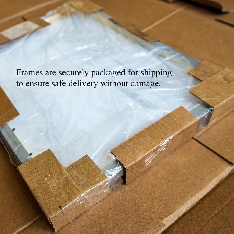 May include: A packaged frame, wrapped in clear plastic, inside a cardboard box. The corners of the frame are protected with cardboard corner protectors. Text on the image reads: "Frames are securely packaged for shipping to ensure safe delivery without damage."