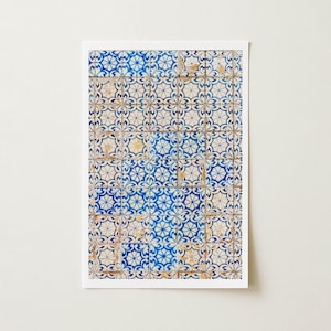 May include: A rectangular print featuring a close-up of traditional Portuguese tiles. The tiles display a repeating floral pattern in shades of blue and white, with hints of yellow and brown. The design is framed by a white border.