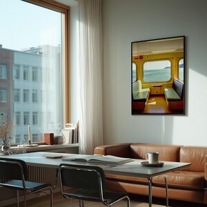May include: A framed wall art print depicting the interior of a yellow train carriage with two facing bench seats and a window view of the ocean. The artwork features a bright color palette with yellow walls, green seat cushions, and a clear blue sea.