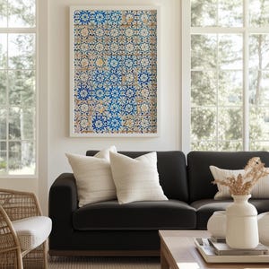 May include: A living room scene featuring a black sofa with cream-colored pillows, a wooden coffee table, and a framed artwork with a blue and white tile pattern. A woven chair and a beige rug complete the cozy interior.