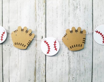 May include: A baseball-themed banner with alternating white baseballs with red stitching and brown paper baseball mitts.