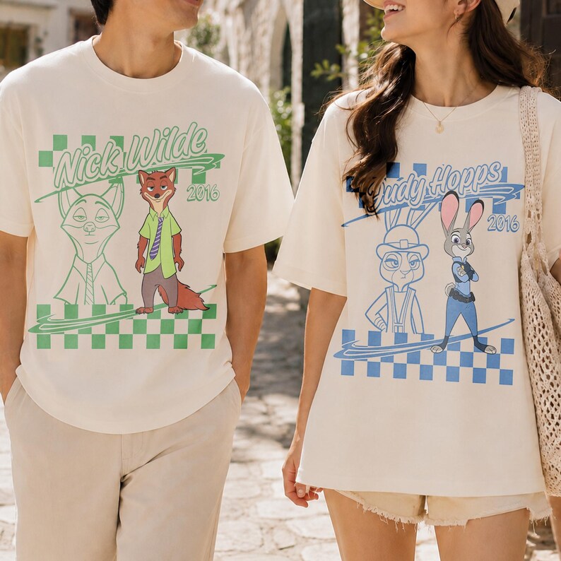 May include: Two off-white short-sleeve t-shirts. The left shirt features a green checkered pattern, a line-art fox, a colored Nick Wilde character, and the text Nick Wilde 2016. The right shirt features a blue checkered pattern, a line-art rabbit, a colored Judy Hopps character, and the text Judy Hopps 2016.