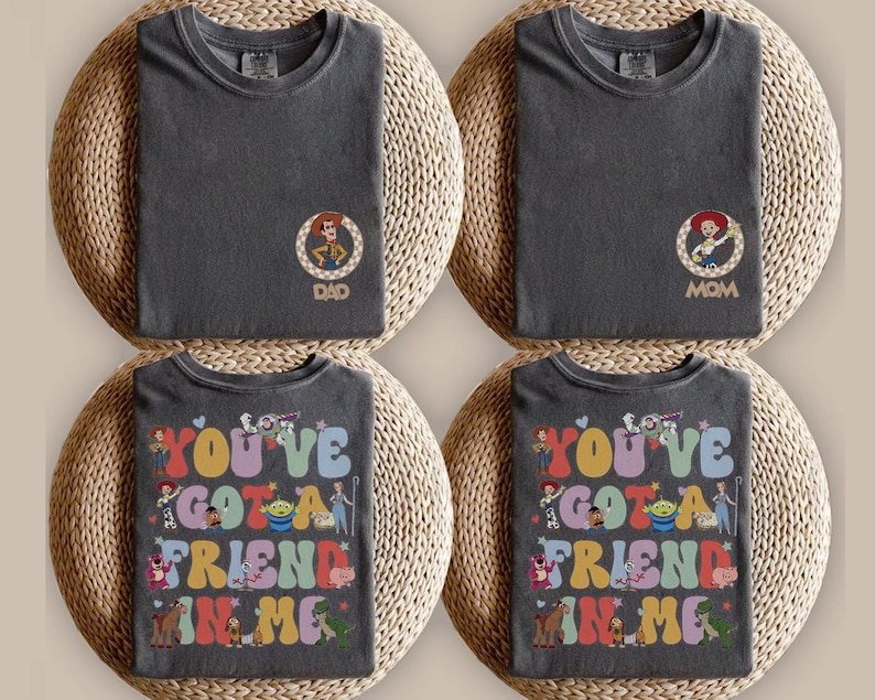 Peut inclure: Quatre t-shirts gris anthracite. Deux t-shirts pr&eacute;sentent un petit motif circulaire repr&eacute;sentant un cow-boy ou une cow-girl avec le texte DAD ou MOM. Deux t-shirts pr&eacute;sentent un grand motif color&eacute; avec le texte YOU'VE GOT A FRIEND IN ME.