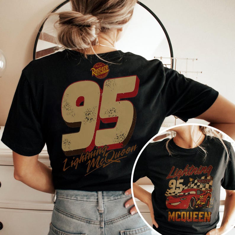 May include: Black t-shirt featuring a distressed design with the number "95" in tan and red, and the words "Lightning McQueen." A smaller image of Lightning McQueen is also visible. The shirt has a vintage, worn look.