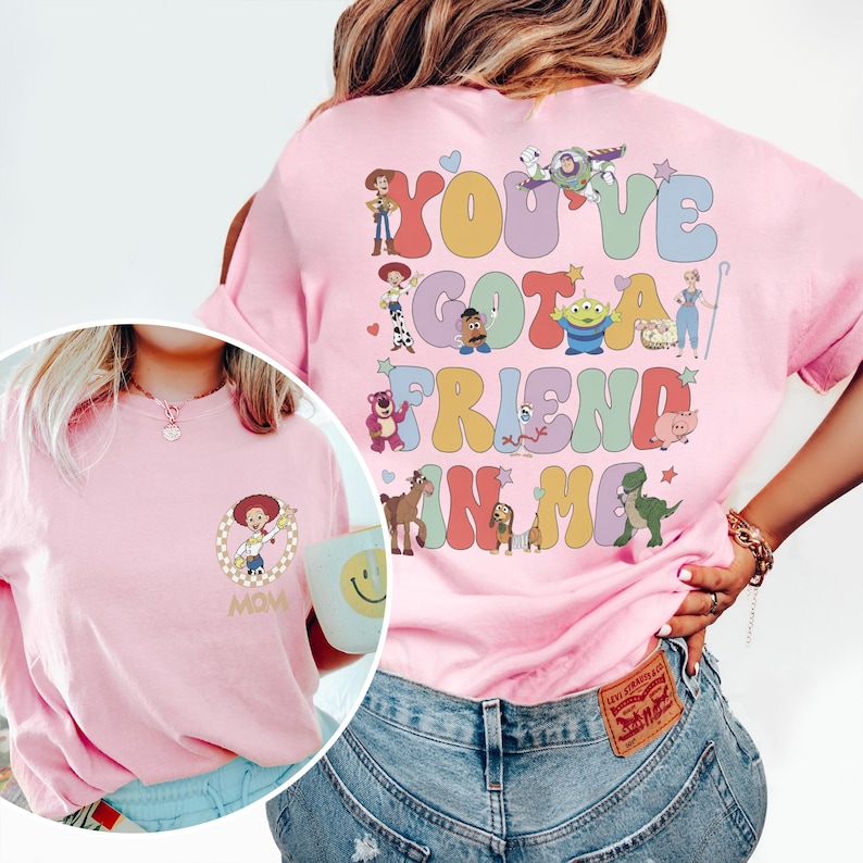 Peut inclure: Un t-shirt rose clair avec un grand motif au dos repr&eacute;sentant divers personnages de Toy Story et le texte "YOU'VE GOT A FRIEND IN ME" en lettres ondul&eacute;es color&eacute;es. La poitrine affiche un petit motif circulaire de Jessie et le mot "MOM".