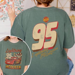 May include: Green t-shirt featuring the number 95 in a distressed style, with "Lightning McQueen" text. The shirt also has a graphic of a red race car and the text "Lightning 95 McQueen".