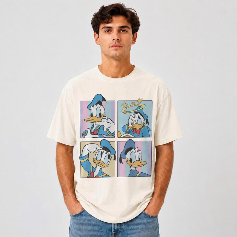 Puede incluir: Una camiseta de manga corta color crema con un estampado gr&aacute;fico de Donald Duck en cuatro paneles distintos. Cada cuadrado muestra al personaje en una pose y expresi&oacute;n diferente, incluyendo una con estrellas alrededor.