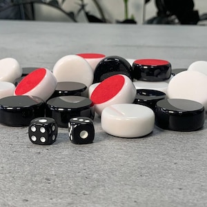 May include: A close-up of a game set with black and white game pieces and two black dice with white dots. The game pieces have red felt on the bottom.