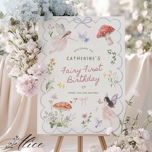 Könnte beinhalten: Ein rechteckiges Schild mit blauem Wellenrand und Aquarellillustrationen von Feen, roten Pilzen, Blumen und Vögeln. Der Text lautet: Welcome to Catherine's Fairy First Birthday. Thank you for coming! Es steht auf einer hölzernen Staffelei.