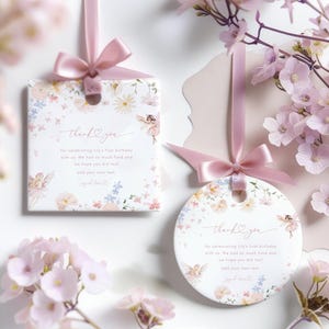 Peut inclure: Deux étiquettes de remerciement avec des motifs floraux et des fées. Le texte sur les étiquettes est "merci d'avoir célébré le premier anniversaire de Lily avec nous. On s'est bien amusés et on espère que vous aussi ! Ajoutez votre propre texte".