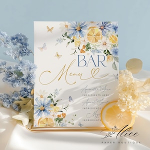Puede incluir: Un letrero decorativo de menú de bar con detalles florales y rodajas de limón. El letrero presenta la palabra "BAR" en azul, "Menu" en dorado y listas de ingredientes. Mariposas y flores adornan los bordes. El letrero está sobre un soporte dorado.