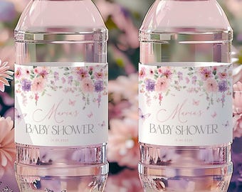 Könnte beinhalten: Zwei durchsichtige Plastikwasserflaschen mit rosa floralen Etiketten, auf denen "Maria's Baby Shower" mit Schmetterlingen steht. Die Etiketten haben ein Aquarell-Blumenmuster mit rosa, lila und weißen Blumen.