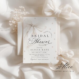K&ouml;nnte beinhalten: Eine cremefarbene Brautparty-Einladung mit einem Aquarell-Bogen und Perlenakzenten. Die Einladung enth&auml;lt den Text "BRIDAL Shower" und Details f&uuml;r Alicias Kate's Party, einschlie&szlig;lich Datum, Uhrzeit und Ort.