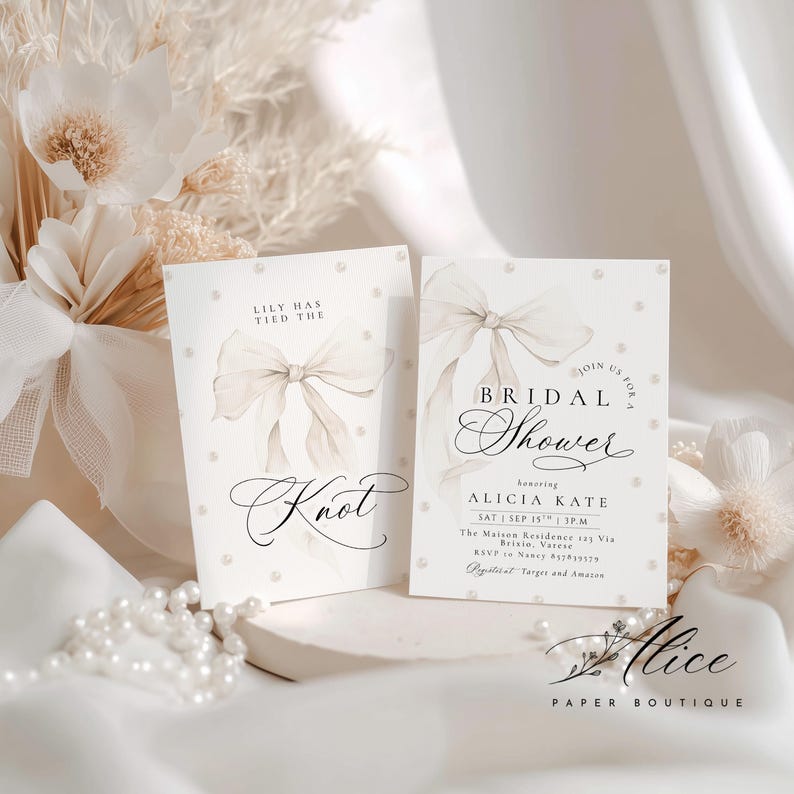 K&ouml;nnte beinhalten: Zwei elfenbeinfarbene Brautparty-Einladungskarten mit einem Aquarell-Schleifendesign und Perlenakzenten. Auf einer Karte steht "Lily has tied the knot". Die andere Karte lautet "Bridal Shower" und enth&auml;lt Eventdetails.