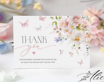 May include: A white thank you card with floral and butterfly illustrations. The card features the words "THANK you" in a mix of serif and script fonts, with a small pink heart. The text below reads, "FOR SHOWERING OUR BABY WITH LOVE! WE HAD SO MUCH FUN AND WE HOPE YOU DID TOO!"