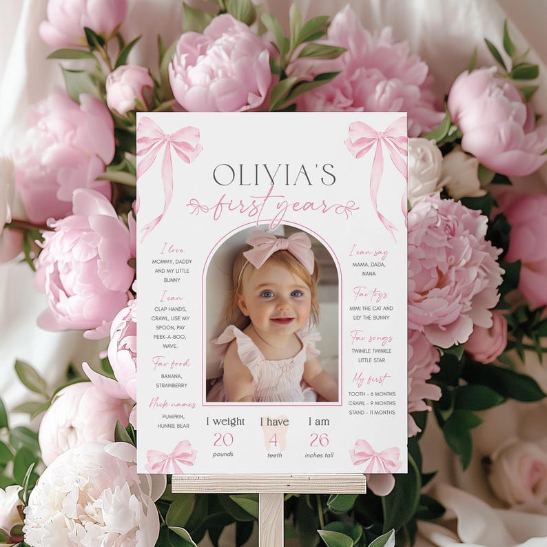 May include: A pink and white printable first birthday milestone poster with a photo of a baby girl. The poster includes the baby's name, Olivia, and details about her first year, including her weight, height, and milestones. The poster is decorated with pink bows.