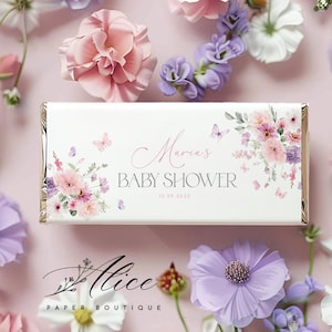 Puede incluir: Un envoltorio de chocolate blanco con un diseño floral y mariposas. El texto "Maria's Baby Shower 15.09.2023" está impreso en el envoltorio.