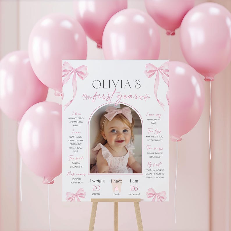 May include: A pink and white first birthday milestone poster with a photo of a baby girl. The poster includes the baby's name, Olivia, and details about her first year, including her weight, height, and milestones. The poster is decorated with pink bows and a watercolor background.