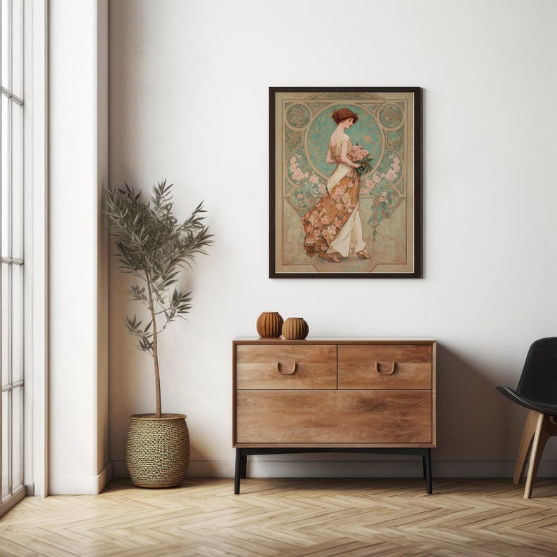 May include: A framed art print featuring a woman in a flowing dress, holding flowers. The artwork has a vintage style with a color palette of beige, brown, and teal. The print is displayed above a wooden dresser with two drawers.