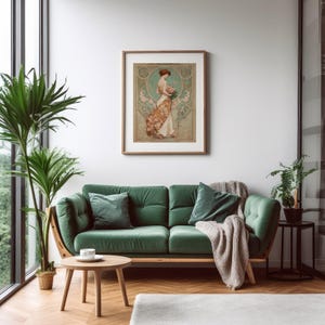 May include: A framed art print featuring a woman in a flowing dress holding flowers, set against a teal and floral background. The print hangs above a green velvet sofa with matching pillows, a wooden coffee table, and a potted plant.