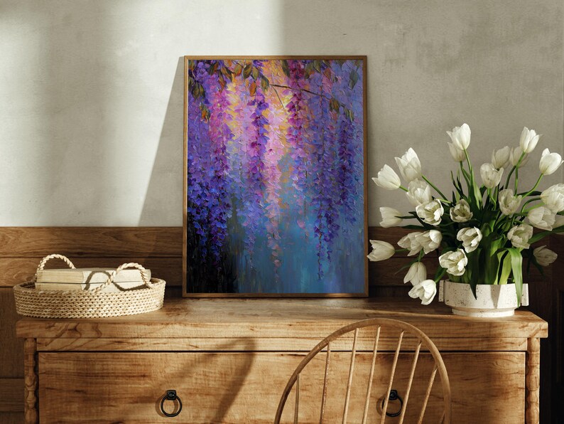 May include: A framed painting depicting wisteria flowers in purple, pink, and blue hues. The artwork is placed on a wooden chest of drawers, with a basket and a vase of white tulips. The painting has a wooden frame.