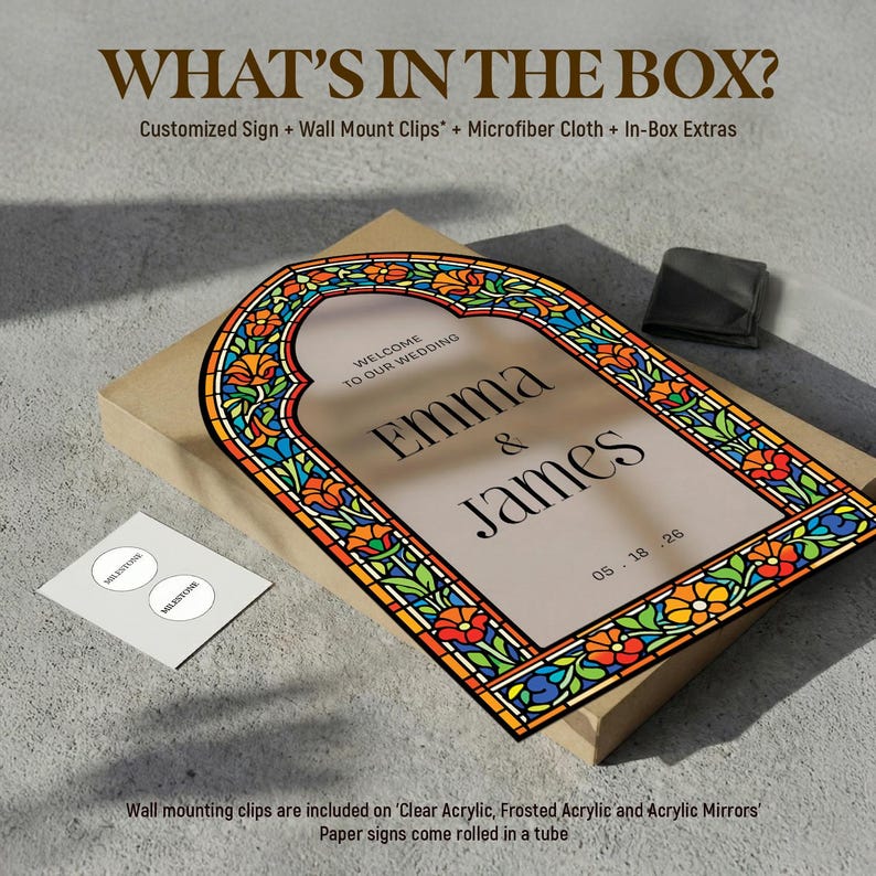 May include: A rectangular wedding sign featuring a stained glass-style border with orange, blue, and green floral patterns. The centre displays the text "WELCOME TO OUR WEDDING", "EMMA & JAMES", and "05.18.26" in black serif font on a beige background.