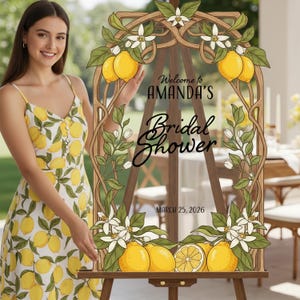May include: A wooden easel sign with a decorative lemon and floral design. The sign reads "Welcome to AMANDA'S Bridal Shower" and "March 25, 2026". The sign is adorned with yellow lemons and white flowers.