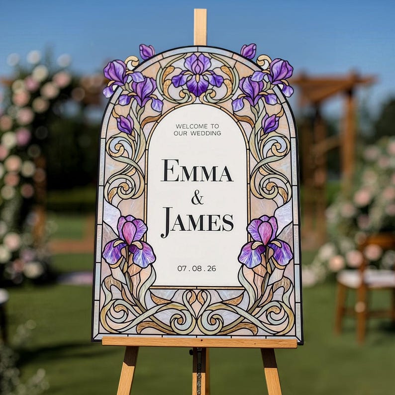 May include: An arched wedding welcome sign featuring a stained glass style border with purple iris flowers and intricate scrollwork. The center white panel displays the text: Welcome to our wedding, Emma & James, and the date 07.08.26.