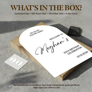 May include: A white arched sign with black text reading SO GLAD YOU'RE HERE! WELCOME TO Meghan's 25TH BIRTHDAY CELEBRATION 07.15.2026. The box includes a customized sign, wall mount clips, a microfiber cloth, and in-box extras with milestone stickers.