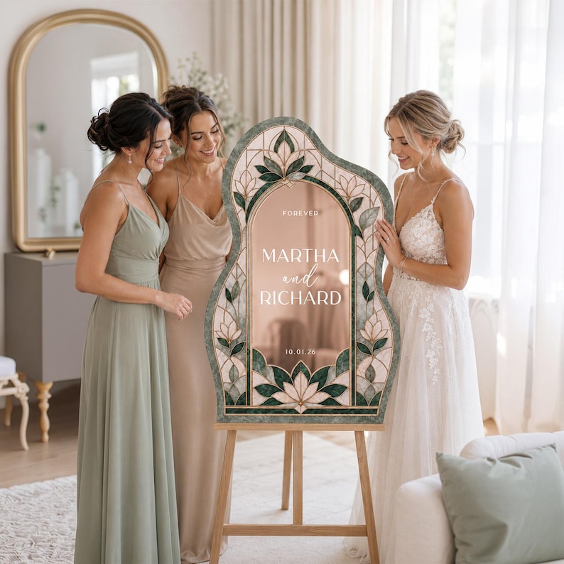 May include: An arched, irregular-shaped wedding sign with a rose gold mirrored center and a dark green, stained-glass-style floral border. The text reads FOREVER, MARTHA and RICHARD, and 10.01.26. The sign is displayed on a light wooden easel.