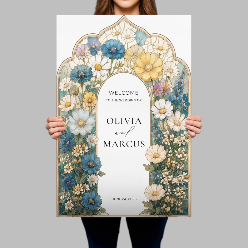 May include: A rectangular wedding welcome sign featuring a decorative archway frame filled with illustrations of blue, yellow, and white flowers. The center text reads: WELCOME TO THE WEDDING OF OLIVIA and MARCUS JUNE 24, 2026, in black serif and script fonts.