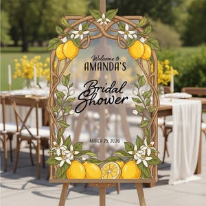 May include: A wooden easel displays a sign for Amanda's Bridal Shower, framed with lemons, white flowers, and green leaves. The sign reads "Welcome to Amanda's Bridal Shower" and "March 25, 2026".
