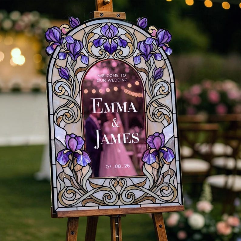 May include: An arched wedding welcome sign featuring a stained glass style border with purple iris flowers and gold scrollwork. The center panel displays the text: Welcome to our wedding, Emma & James, 07.08.26, in white lettering on a dark background.
