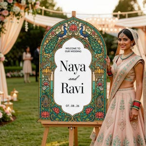 K&ouml;nnte beinhalten: Ein bogenf&ouml;rmiges Hochzeitsschild auf einer Holzstaffelei mit einem Rand im Buntglas-Stil, verziert mit Pfauen- und Lotusblumenmotiven. Der wei&szlig;e Text in der Mitte lautet Welcome to our wedding, Naya and Ravi, sowie das Datum 07.08.26.