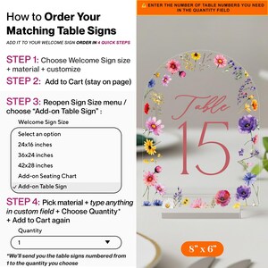 May include: An arched clear acrylic table sign featuring a colourful floral border with pink, purple, yellow, and blue wildflowers. The sign displays the text "Table 15" in a pink serif font. An orange label at the bottom indicates 20.3 x 15.2 cm.