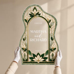 May include: An arched, wavy-edged sign featuring a stained glass-style border in shades of dark green, cream, and gold. The center is clear with white text reading FOREVER, MARTHA and RICHARD, and 10.01.26. The design includes floral motifs.