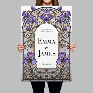 May include: A rectangular wedding welcome sign featuring a stained glass style border with purple iris flowers and swirling gold lines. The center white panel displays the text: WELCOME TO OUR WEDDING, EMMA & JAMES, and the date 07.08.26.