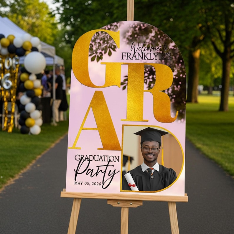 May include: A graduation party sign on an easel. The sign has a pink background with gold lettering that reads "GRADUATION Party" and "Welcome to Frankly". A photo of a graduate is included. The date "MAY 05, 2026" is also displayed.
