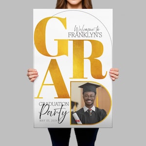 May include: A white graduation party poster with gold text that reads "GRAD" and "Party". The poster includes a photo of a graduate in a cap and gown, and the text "Welcome to Franklyn's" and "May 05, 2026".