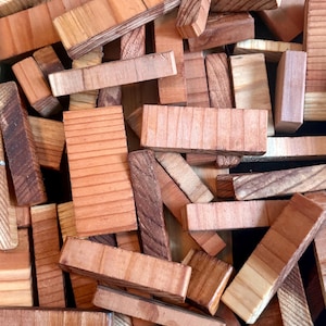 Puede incluir: Una colección de bloques de madera de varios tonos marrones y beige. Los bloques son rectangulares y de diferentes tamaños, algunos con vetas de madera visibles y otros con superficies lisas. Los bloques están dispersos, creando una apariencia texturizada y táctil.