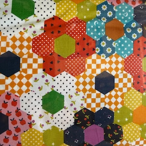 May include: A fabric featuring a patchwork design of multicolored hexagons. The pattern includes various prints such as orange and white checkers, red with black hearts, white with black polka dots, blue with white stars and flowers, and pink with red apples.